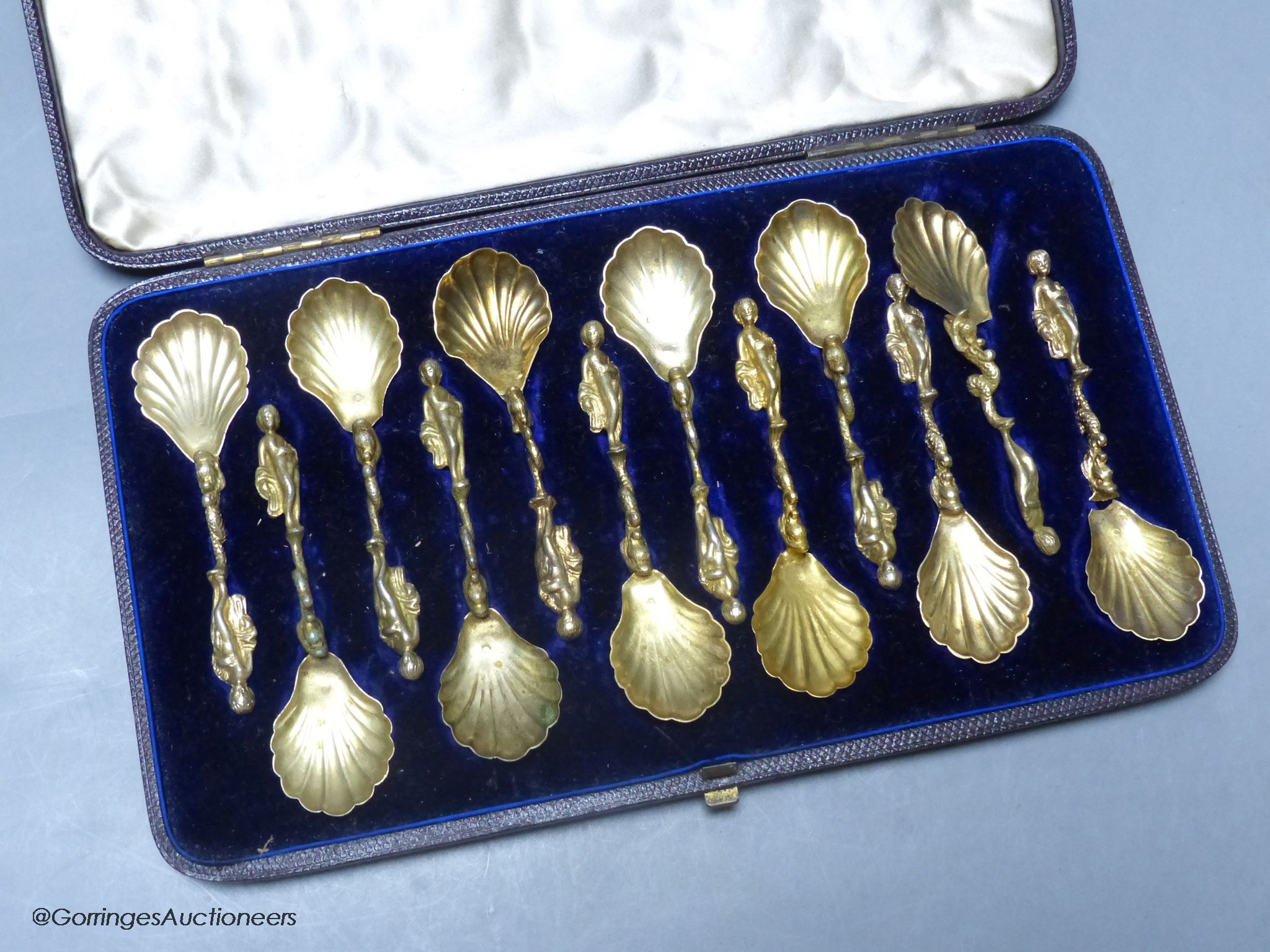 A 19th century cased set of twelve Italian? gilt white metal spoons, with figural and dolphin stem and shell bowls (two broken)